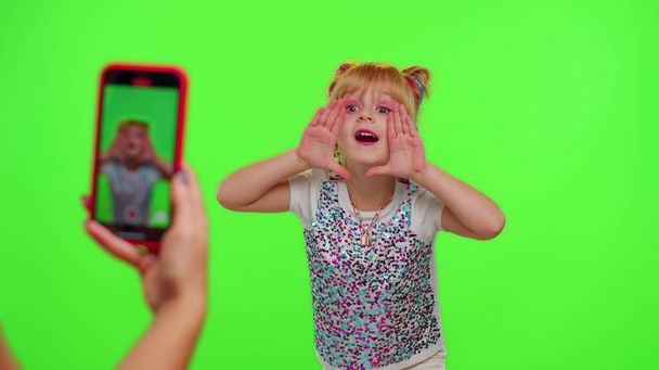 Αξιαγάπητο μικρό κορίτσι blogger μπροστά από το τηλέφωνο κάμερα εγγραφή βίντεο απολαμβάνουν χορευτικό περιεχόμενο στο κλειδί chroma - Φωτογραφία, εικόνα