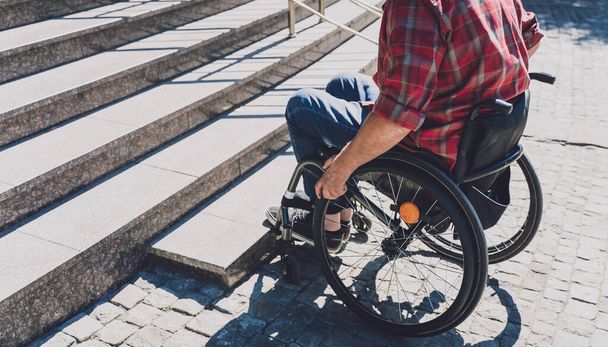 Young man with a physical disability in a wheelchair in front of the stairs - Valokuva, kuva