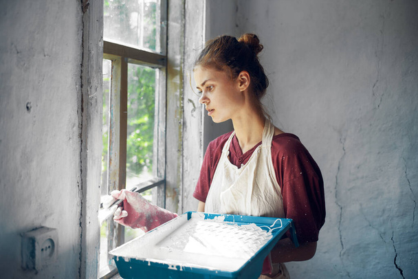 woman in apron painter repair painting window - Zdjęcie, obraz