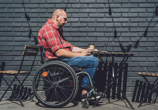 Freelancer with a physical disability in a wheelchair working at the street cafe - Fotoğraf, Görsel
