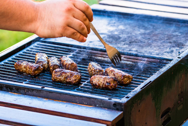 Préparation de rouleaux de viande appelés mici ou mititei sur barbecue. gros plan du gril avec feu ardent avec flamme et fumée. - Photo, image