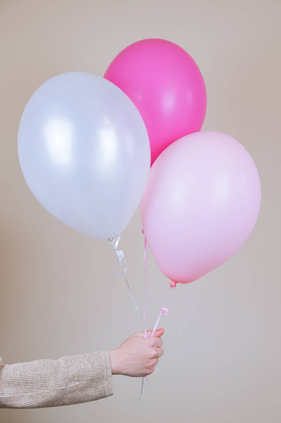 A female hand holds a three helium balloon. The concept of holiday decorations, accessories for the children's holiday. Vertical image - 写真・画像