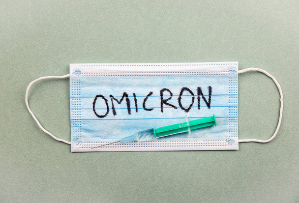 Nieuw Coronavirus Covid-19 mutatie Omicron concept. Medisch masker, spuit en tekst met letters Omicron. - Foto, afbeelding