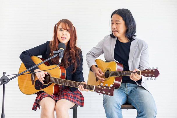 Asian family duo band with two guitarist of father and daughter on white background while playing live acoustic concert for music, artist, musician - Fotó, kép