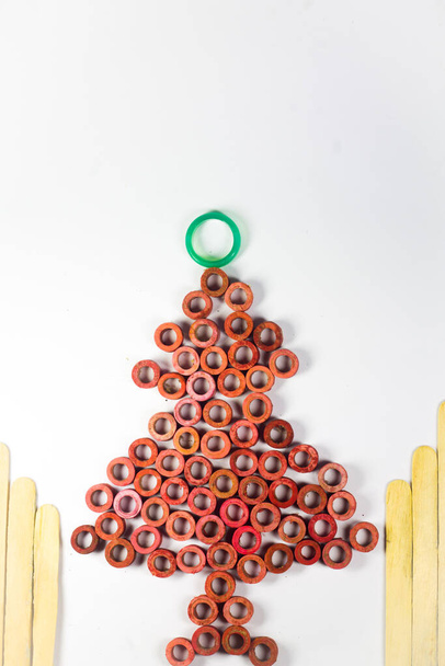 Christmas tree on an isolated white background. DIY red circle made of elastic rubber and wooden sticks. - Fotografie, Obrázek
