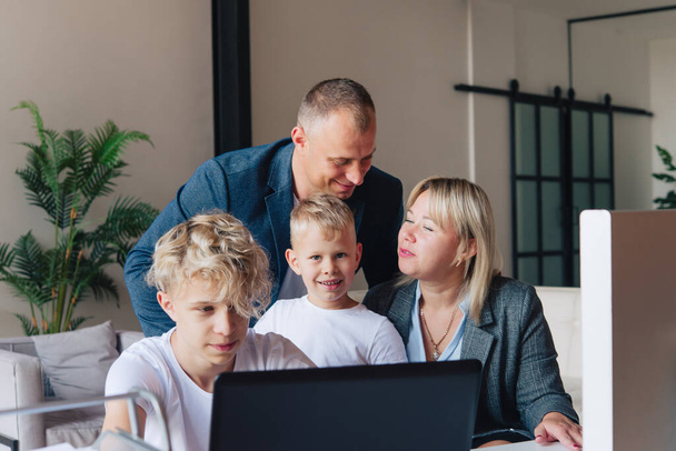 Familia feliz, papá, mamá y dos niños, agitando sus manos durante una videollamada a través de una computadora portátil en casa. - Foto, imagen