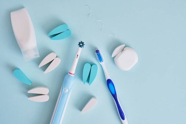 toothpaste, dental floss, electric and plastic toothbrushes on a blue background, which brushes are more effective in cleaning the oral cavity and are more eco-friendly - Photo, Image