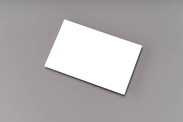 Modern business card mockup template on gray background. Top view flat lay of a card. Mock-up design for branding, advertising and design - Foto, imagen