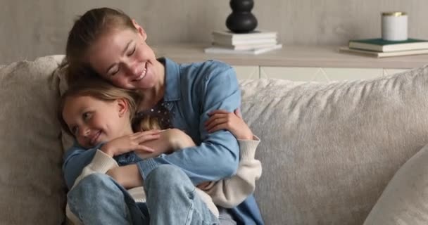Young mother sit on couch hold preteen girl in arms - Filmmaterial, Video