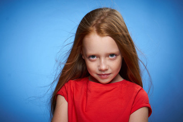 cheerful cute red-haired girl childhood blue background - Foto, imagen