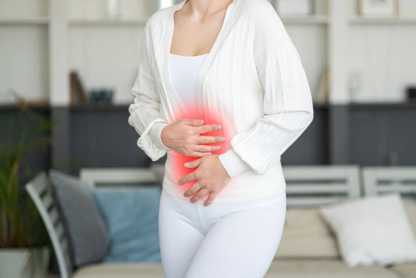 Menstrual pain, woman with stomachache suffering from pms at home, endometriosis, cystitis and other diseases of the urinary system, painful area highlighted in red - Φωτογραφία, εικόνα