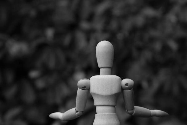Деревянный кукольный манекен с вытянутыми руками. Черное и белое. - Фото, изображение