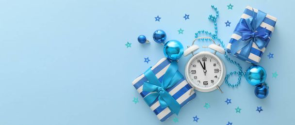 Wekker klok met geschenken en kerstversieringen op blauwe achtergrond met ruimte voor tekst - Foto, afbeelding