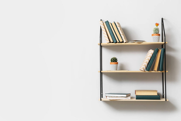 Modern shelves with books hanging on light wall - Fotoğraf, Görsel