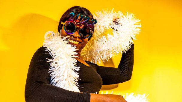 Femme africaine avec des lunettes de soleil sombres dans lesquelles les chiffres 2022 sont vus avec un boa blanc entourant son cou - Photo, image