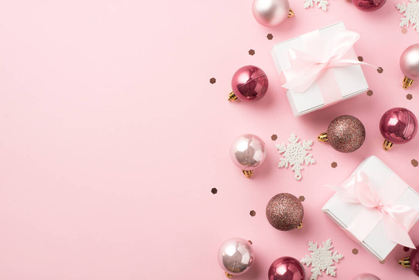 Вид зверху фото рожевих різдвяних прикрас кулі сніжинки конфетті і білі подарункові коробки з рожевими стрічками бантами на ізольованому пастельному рожевому фоні з копійкою
 - Фото, зображення