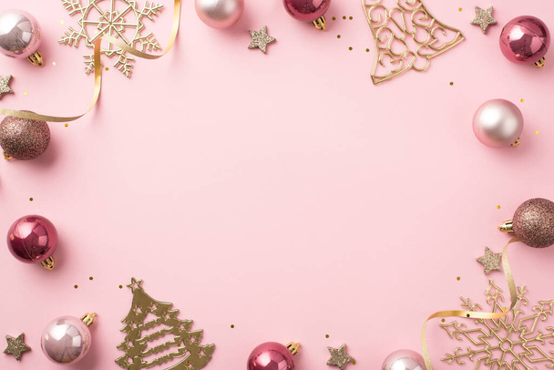 Foto von oben Weihnachtsdekoration rosa Kugeln Gold Glocke Kiefer schneeflockenförmigen Ornamenten glühende Sterne Serpentin und Pailletten auf isolierten pastellrosa Hintergrund mit leeren Raum in der Mitte - Foto, Bild