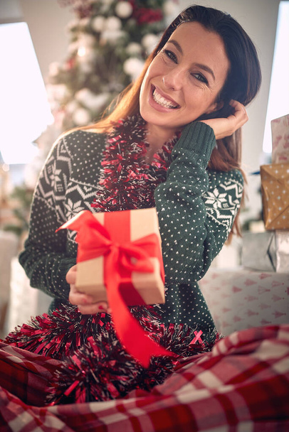Happy  woman opening Christmas gift at home. Magic holiday. - Фото, изображение