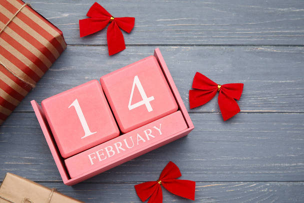 Calendar with date of Valentines Day, gift boxes and red bows on grey wooden background, closeup - Photo, image