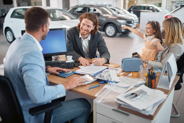 Smiling man with his family buying a new car. - Photo, Image
