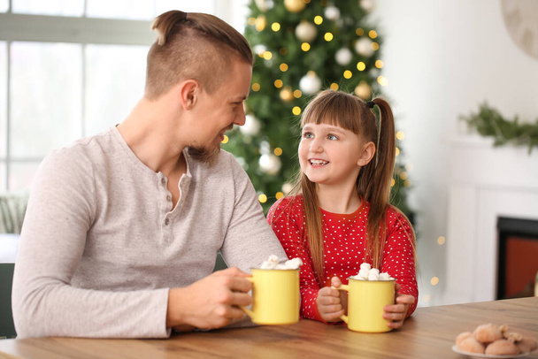 Fille et père heureux avec des tasses de cacao chaud à la maison - Photo, image