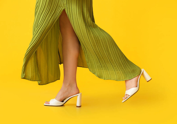Woman in trendy shoes walking on color background - Fotó, kép