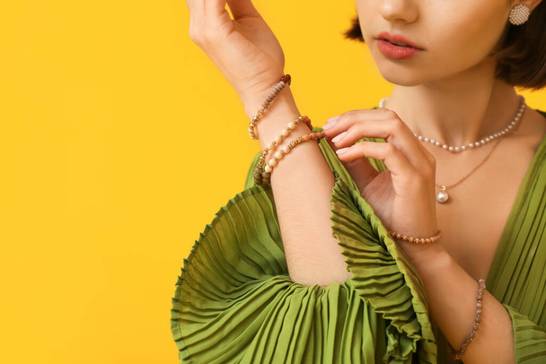 Woman touching elegant bracelet on color background, closeup - Fotó, kép