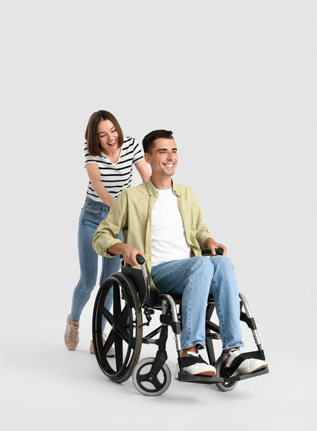 Młody mężczyzna na wózku inwalidzkim i jego żona na jasnym tle - Zdjęcie, obraz