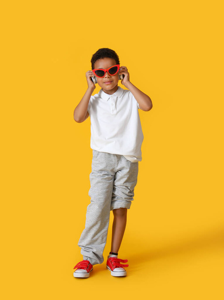 Крутий афро-американський хлопчик слухає музику на кольоровому фоні - Фото, зображення