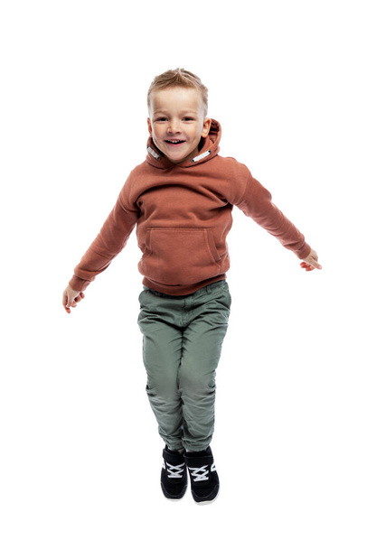 The little boy is emotionally jumping. Freedom, joy and positivity. Isolated on white background. Vertical. - Photo, image