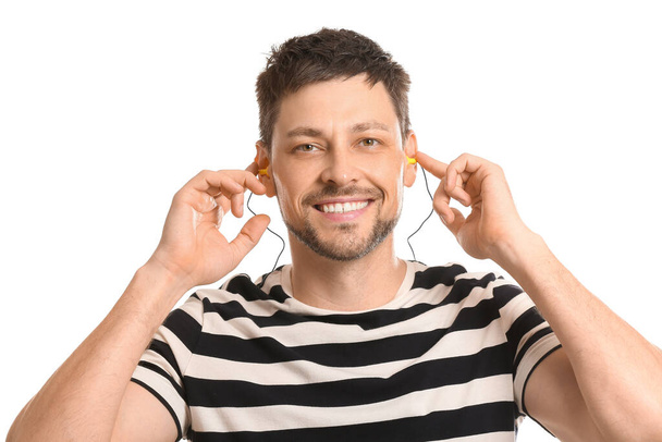 Sorrindo homem bonito com tampões de ouvido no fundo branco - Foto, Imagem