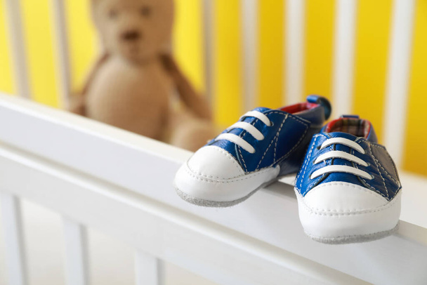 Cute baby shoes on white crib - Foto, Imagem