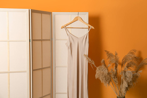 Folding screen with dress and pampas grass near orange wall - Photo, Image