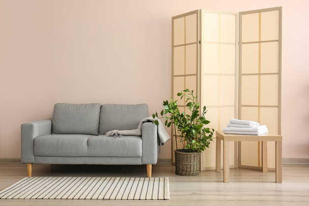 Interior elegante com sofá e tela dobrável perto da parede no quarto - Foto, Imagem