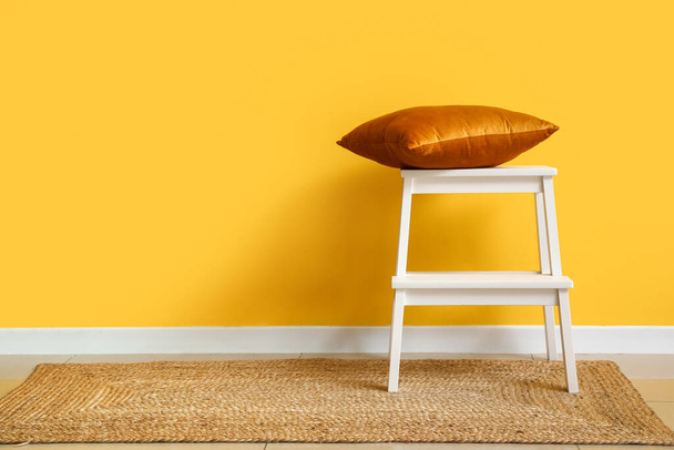 White step stool with pillow near yellow wall - Foto, Imagem