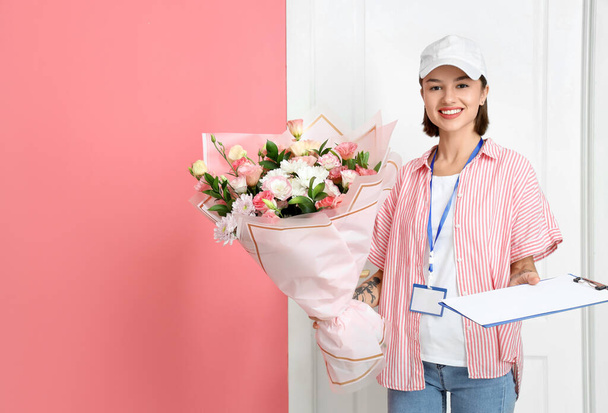 Female courier with bouquet of flowers in hall - Фото, зображення
