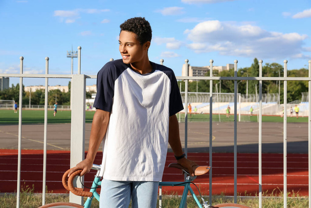 アフリカ系アメリカ人の10代の少年、競技場近くの自転車 - 写真・画像