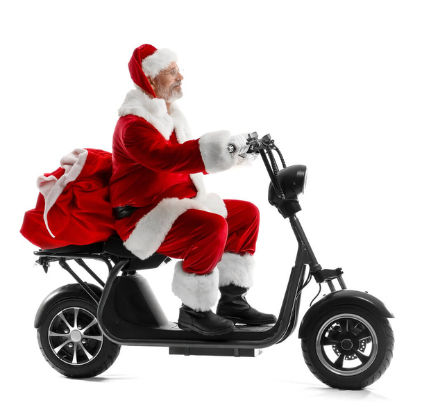 Santa Claus riding electric scooter with Christmas presents on white background - Photo, Image
