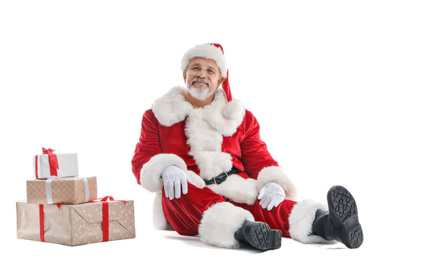 Santa Claus and stack of Christmas presents on white background - Photo, Image