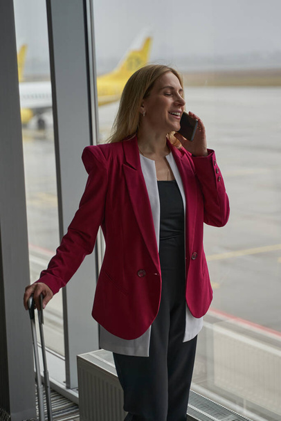Mujer sonriente contestando llamada en smartphone en aeropuerto - Foto, imagen