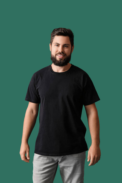 Handsome man in black t-shirt on green background - Фото, изображение
