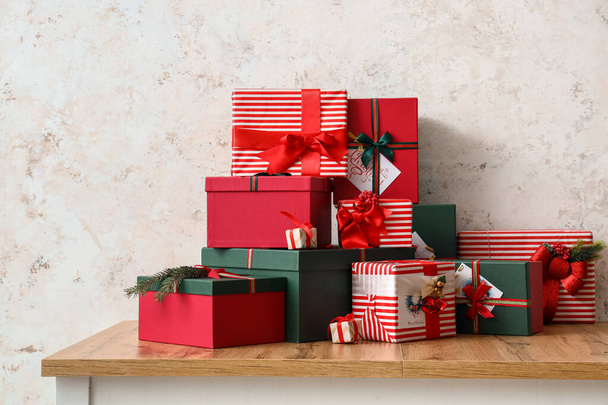Diferentes cajas de regalo en mesa de madera cerca de pared ligera - Foto, imagen