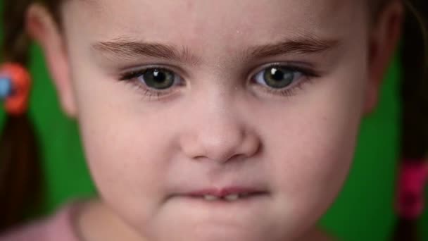 Kislány pislogó szemek, lassított felvétel egy gyermek, portré egy zöld háttér. - Felvétel, videó