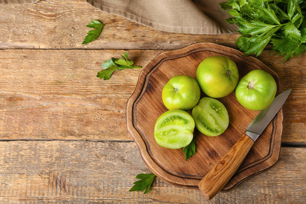 Board with green tomatoes and parsley on wooden background - Photo, Image