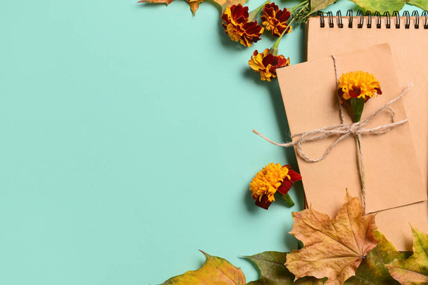 Notebook with card, flowers and fallen leaves on blue background - Foto, immagini
