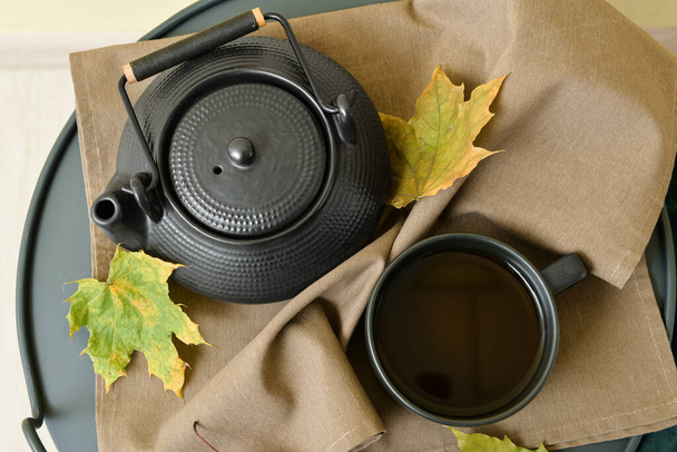 Tea pot, cup of hot beverage and autumn leaves on table - Photo, Image