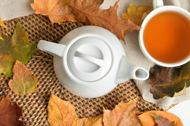 Théière, tasse de boisson chaude et feuilles d'automne sur la table - Photo, image