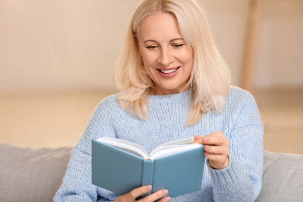 Kaunis kypsä nainen lukee kirjaa kotona - Valokuva, kuva