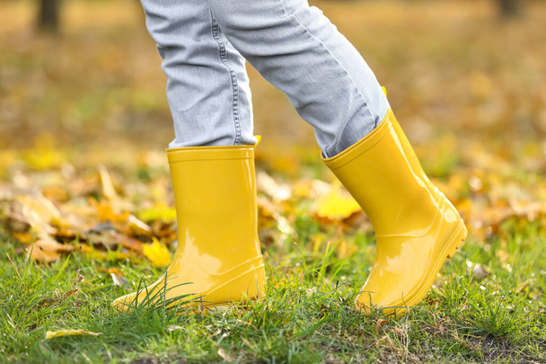 Mujer con botas de goma amarillas caminando en el parque de otoño, primer plano - Foto, Imagen