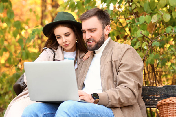 Молодая пара с ноутбуком в осеннем парке - Фото, изображение